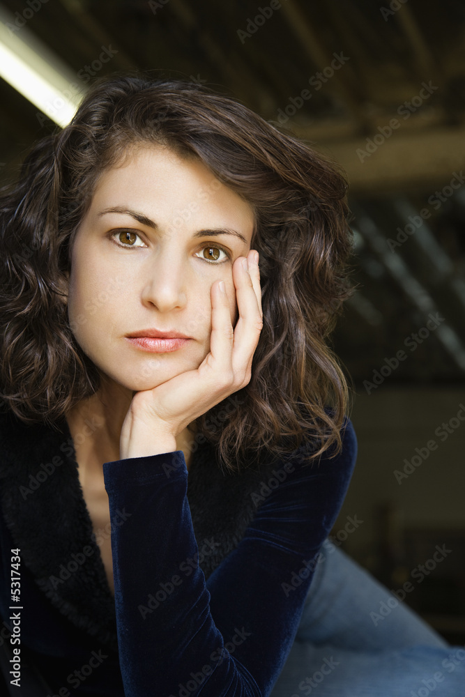 Portrait of woman with head on hand making eye contact. Portrait of woman with head on hand making eye contact.