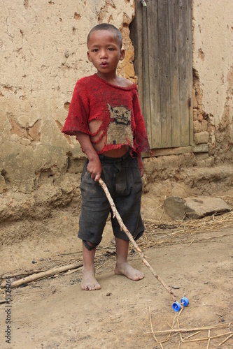 enfant malgache avec son baton çà roulettes