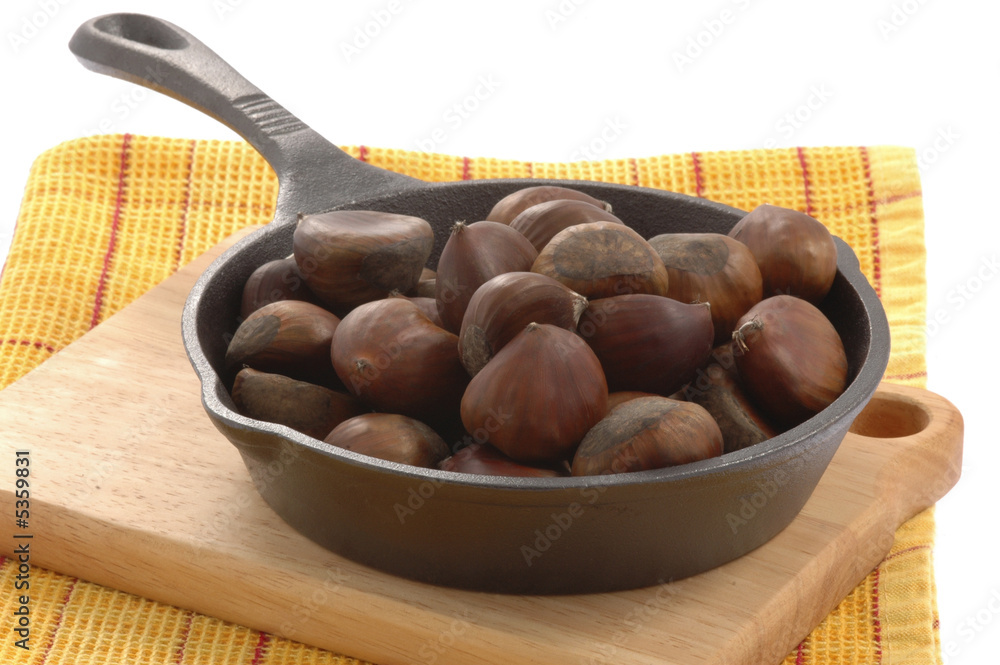 Obraz premium Cast iron pan filled with roasted chestnuts.
