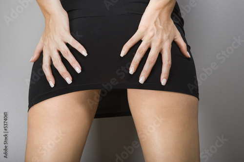 Caucasian female wearing miniskirt with hands on buttocks.