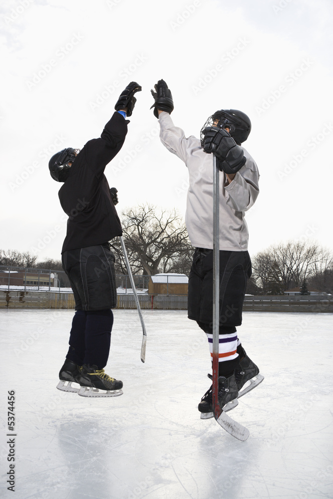 Two boys in ice hockey uniforms giving eachother high five. Stock-Foto |  Adobe Stock