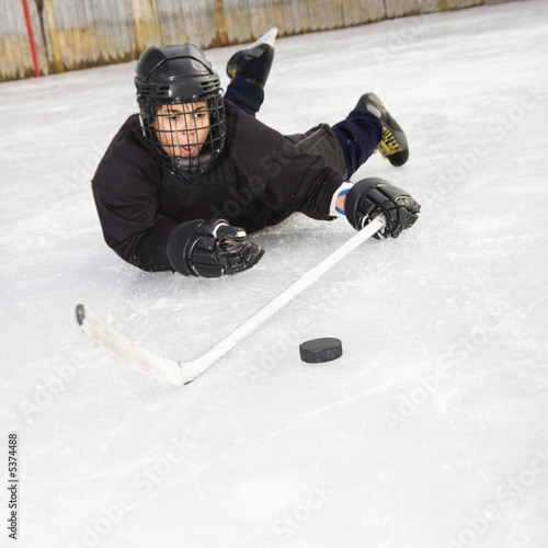 Photography Ice hockey player boy in uniform sliding on ice.