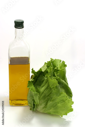 Green lettuce with olive oil in transparent bottle