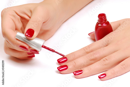 Woman brushing her nails in the red color