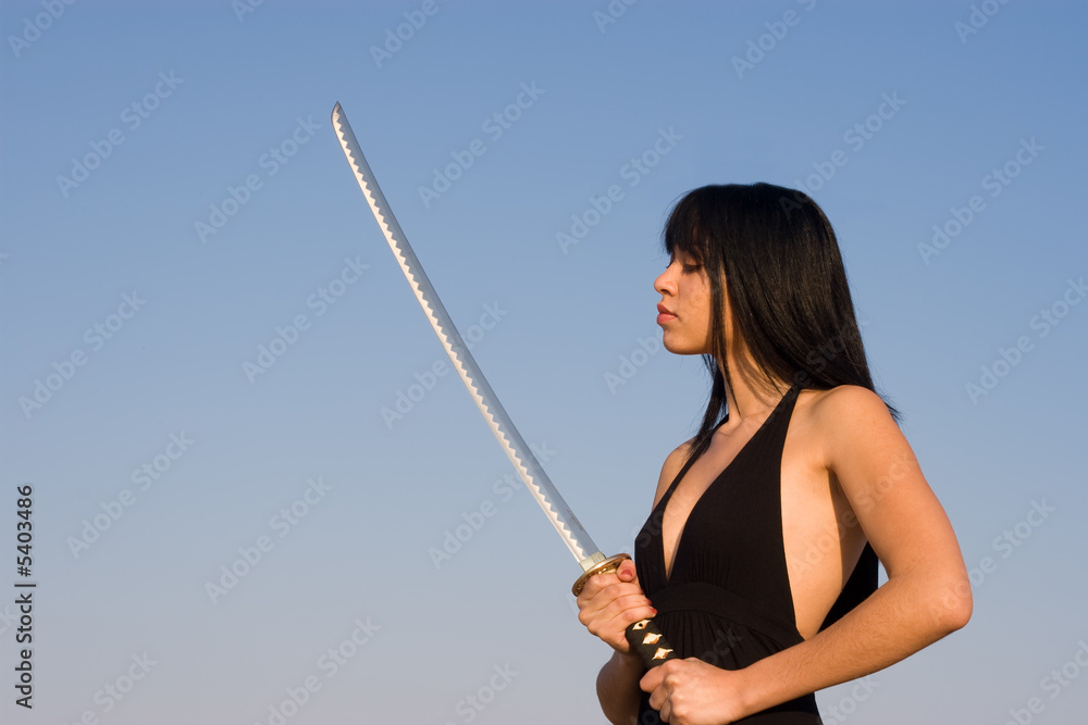 Asian model posing with a sword against blue sky Asian model posing with a sword against blue sky