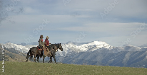 Cowboys on horseback riding the range. 