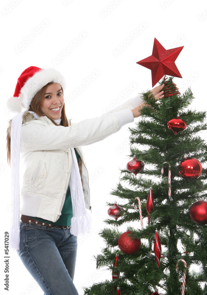 A pretty woman putting a star on the Christmas tree A pretty woman putting a star on the Christmas tree