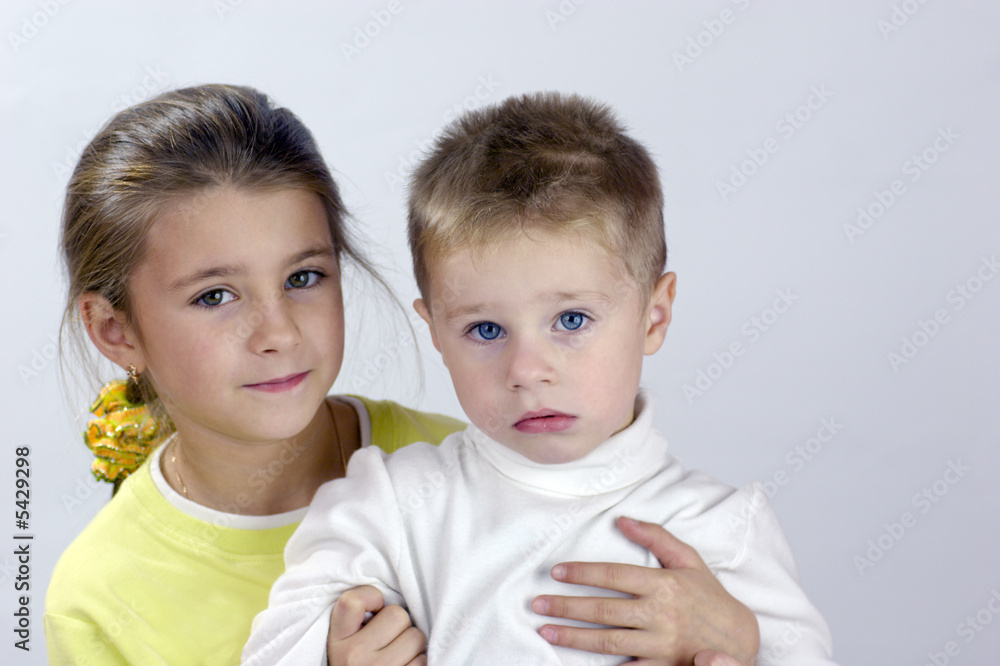 Adorable sister and brother sitting together and looking at you Adorable sister and brother sitting together and looking at you