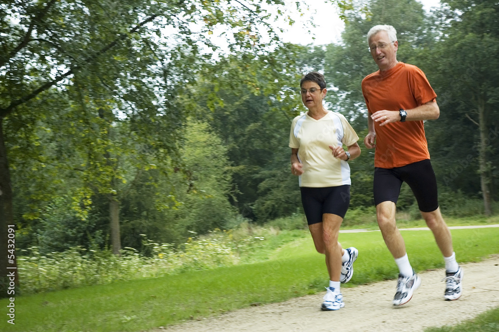 Senior couple running through the woods. Some motion blur.