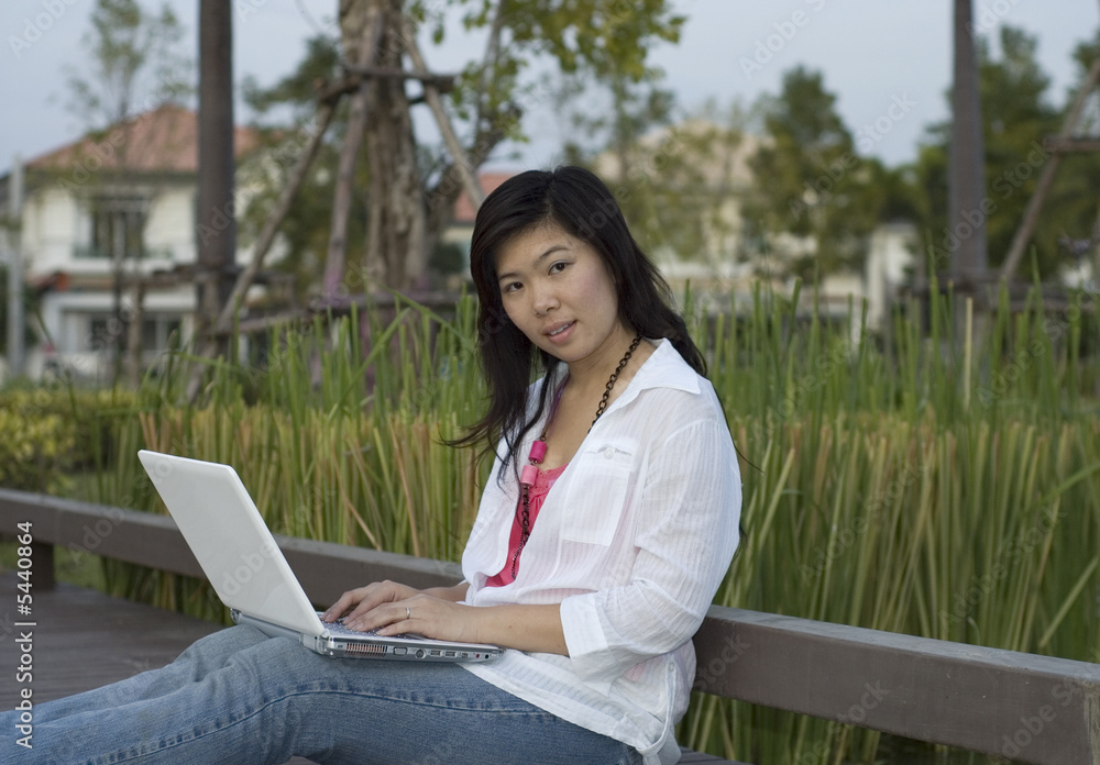 Asian female outdoors with her laptop computer Asian female outdoors with her laptop computer
