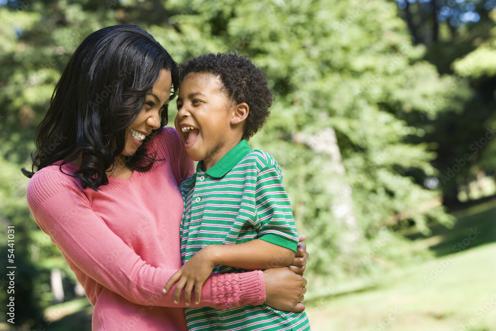 Mother holding young son and smiling.