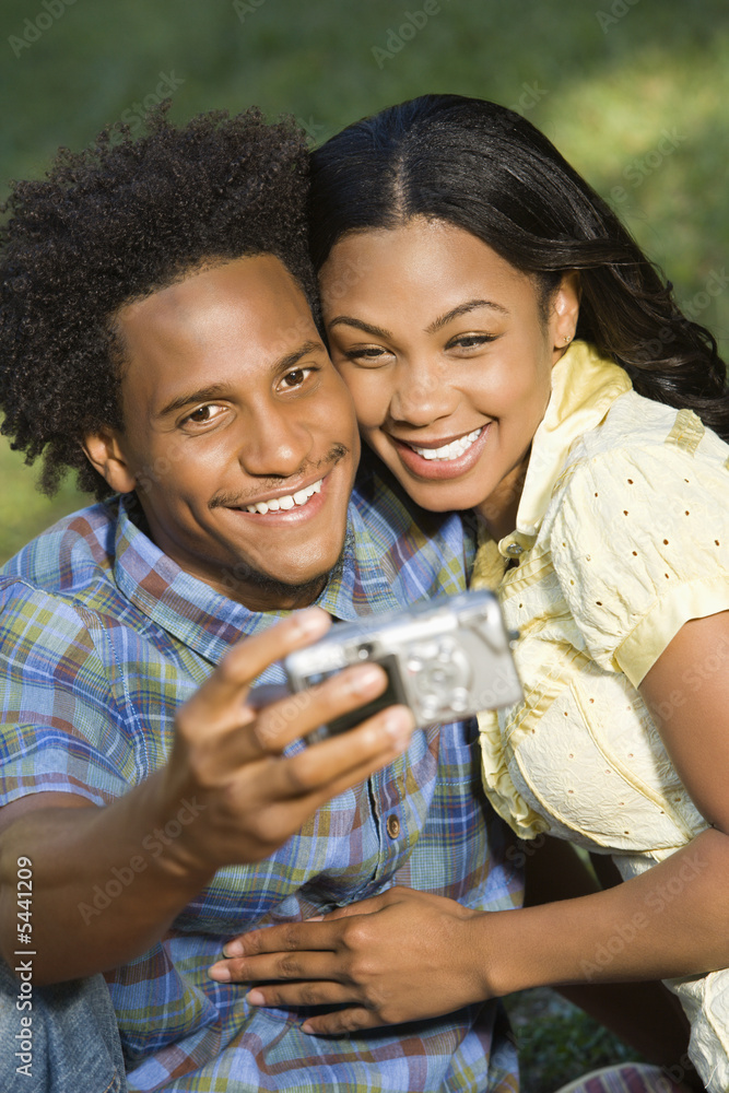 Happy couple taking pictures together in park with camera. Happy couple taking pictures together in park with camera.