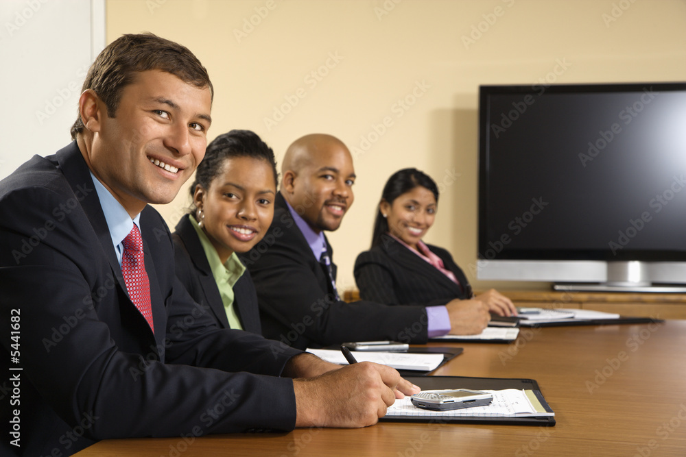 Businesspeople in meeting with flat display in background. Businesspeople in meeting with flat display in background.
