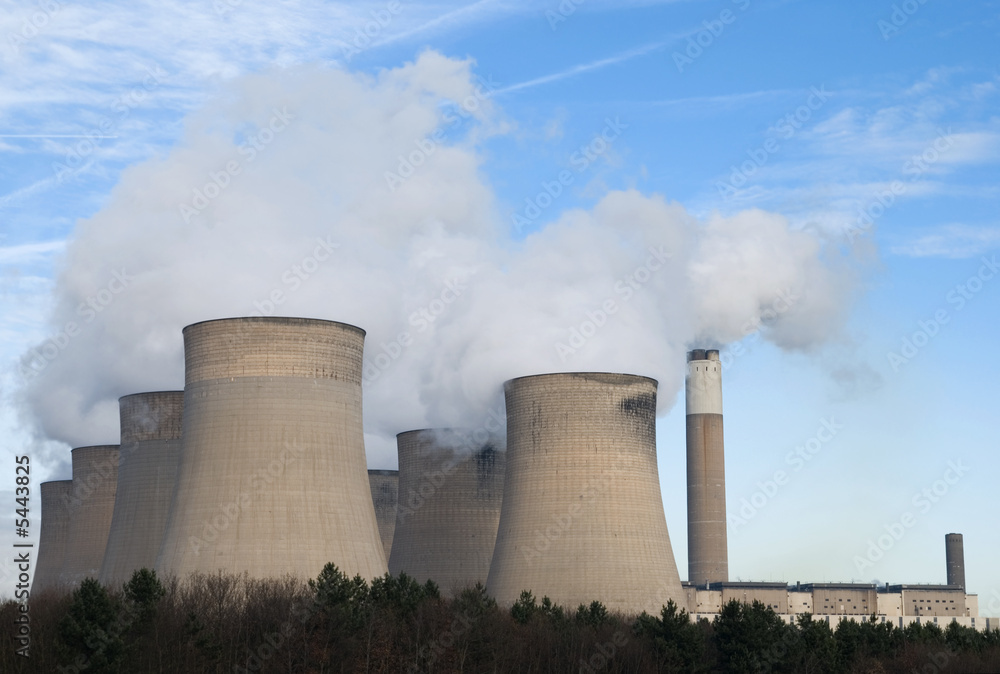 Powerstation cooling towers emitting steam against blue sky