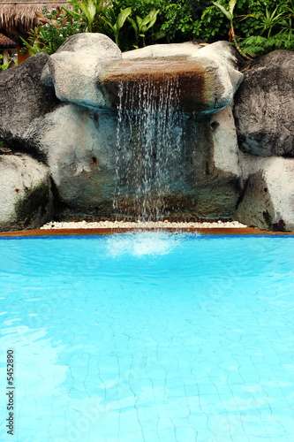 Man-made waterfall flowing into a swimming pool © Gina Smith