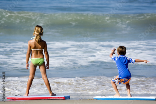 Two kids playing with body boards on the beach