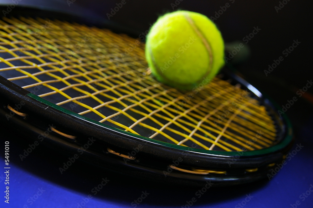 Closeup of a tennis racket and ball