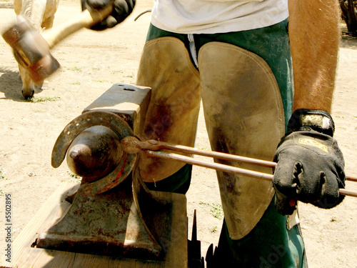 Farrier finishing a horeshoe on an anvil photo