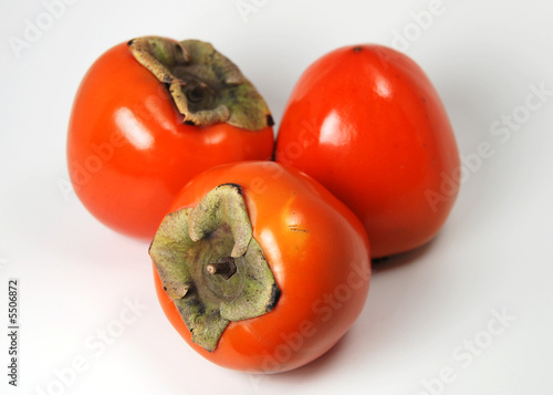 three organic hachiya persimmons, isolated on white.