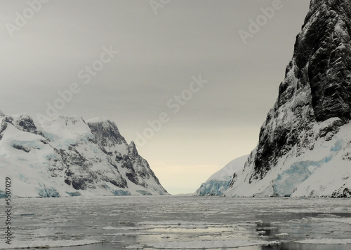 sunrise at lemaire channel over brash ice in antarctica.