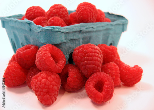 fresh raspberries spilling out of their pint container