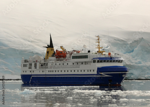 ship in front of glacial wall in antarctica.