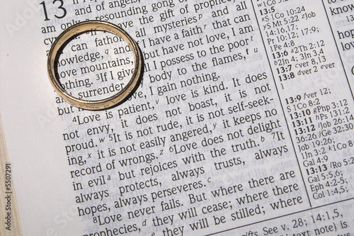 A wedding ring on a bible open to marriage scripture.