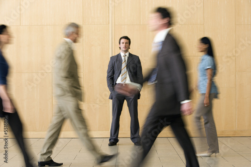 Confident businessman with team walking past him