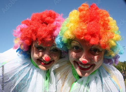 Two bizzare clowns in colored wigs upon blue sky