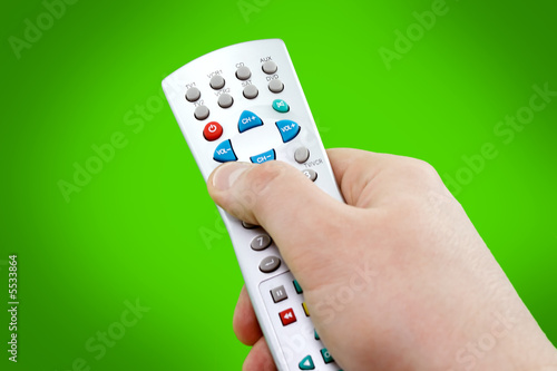 remote control in hand on green background
