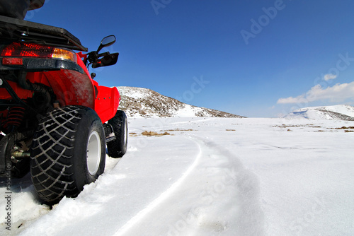 red quad bike in snow mountain scenery © io