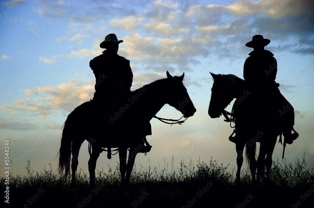 Cowboys on a Montana ridge at dawn, back lit by the rising sun Cowboys on a Montana ridge at dawn, back lit by the rising sun
