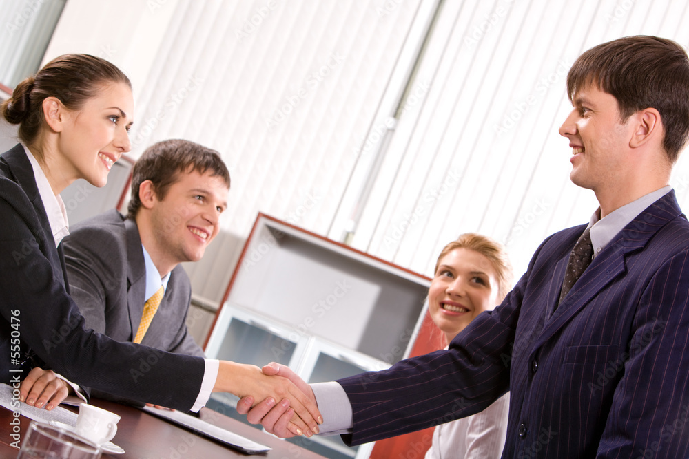 Businessman and woman shaking hands at meeting in the office Businessman and woman shaking hands at meeting in the office
