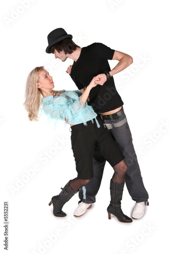 girl in cyan blouse dances with boy in black hat on white