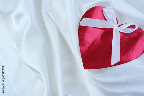 Fotografie Red heart with ribbon on white satin