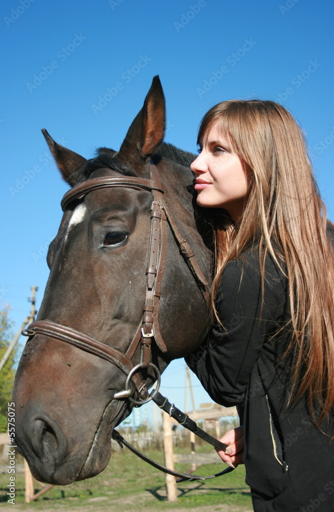 Fototapeta premium Long-haired female model with black horse close-up portrait