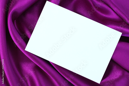Foto Blank white card on purple and magenta colored satin cloth.
