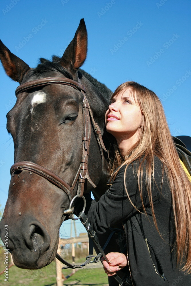 Fototapeta premium Long-haired female model with black horse close-up portrait