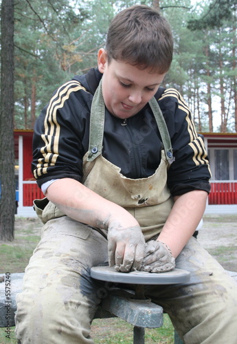 Young boy potter working with clay on wheel