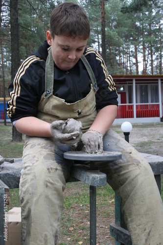 Young boy potter working with clay on wheel