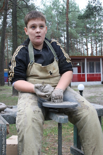 Young boy potter working with clay on wheel