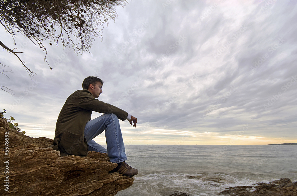jeune homme assis seul face à la mer solitude tristesse