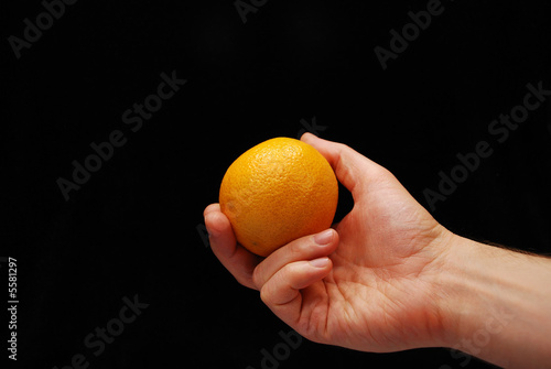 The hand holds an orange