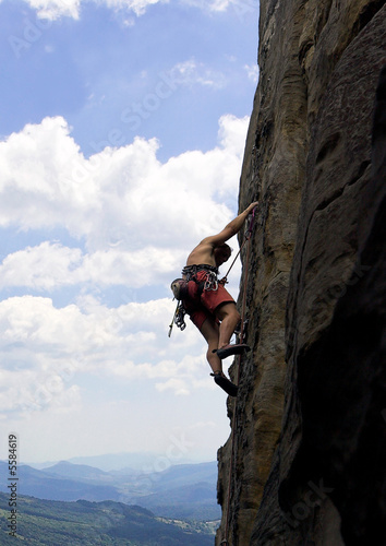 Climber on a vertical rock, high above valley