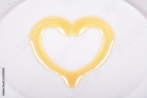 Yellow honey in the shape of heart on a white plate