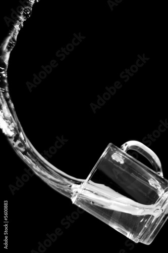 Water pours out from a glass. Black background