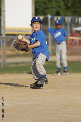 young boy on a baseball field with ball in hand
