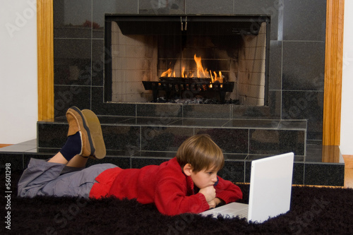 Boy at Fireplace on Computer. photo