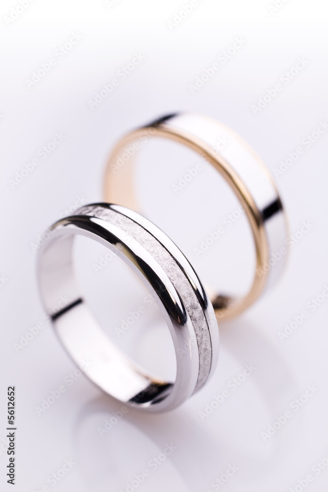 Two white gold engagement rings over a white 
