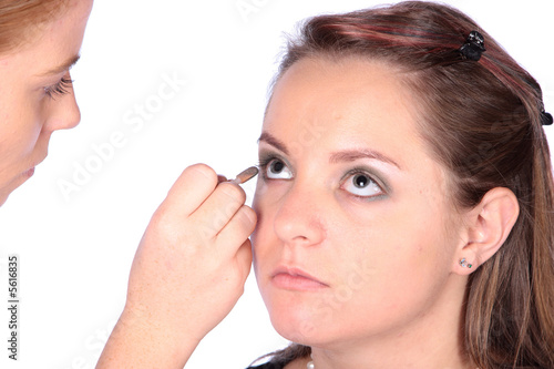 Makeup artist applying eye liner to model's eyes